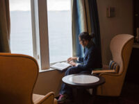 Quark Expeditions_Arctic Saga_Fair Isle, Faroes, and Spitsbergen_Birds & Bears_pax_reading_inside_ship_ATL_library_Credit_AcaciaJohnson