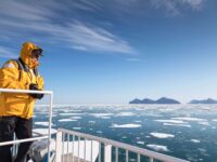 Quark Expeditions_Arctic Saga_pax_aboard_ship_ice_OCN_east_greenland_Credit-AcaciaJohnson