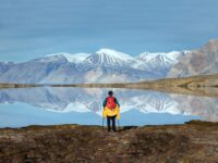 QuarkExpeditions_ThreeArcticIslands-Northbound_pax_alone_in_reflection_landscape_ella_island_east_greenlandCredit-Acacia Johnson